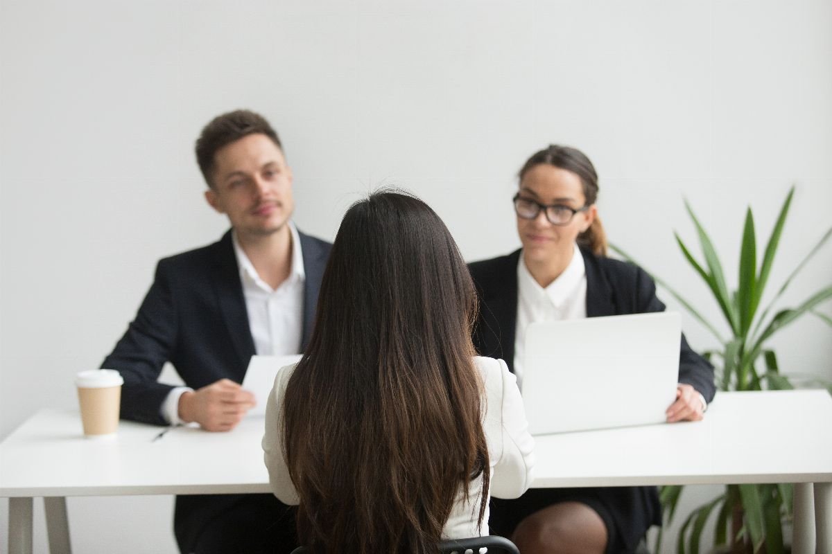 Two interviewers speaking with a candidate across a desk